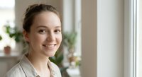 Young professional Caucasian businesswoman smiling confidently in modern office environment with natural lighting for corporate marketing materials.