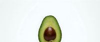 Fresh avocado half with brown pit on clean white background isolated for healthy food design and culinary projects.
