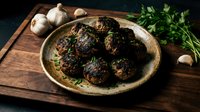 Homemade meatballs with herbs served in rustic ceramic bowl on wooden cutting board with fresh garlic and parsley for cooking and dining concepts.