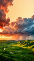 Dramatic sunset storm clouds illuminate rolling green hills with winding river below, creating striking contrast between golden sky and lush landscape for nature and weather projects.