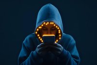 Young person in blue hoodie illuminated by glowing circle of lights and phone screen in dark atmosphere creates mysterious social media addiction concept.