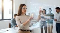 Professional businesswoman with glasses interacting with futuristic holographic interface displaying data analytics and charts in modern office environment.