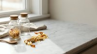 Natural vitamin supplements in glass jars on marble kitchen counter with morning sunlight for healthy lifestyle and wellness routine.