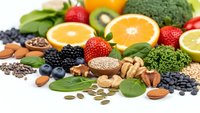 Fresh organic fruits vegetables nuts seeds berries arranged on white background healthy nutrition superfood antioxidants vitamins minerals diet wellness.