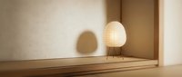 Modern floor lamp with paper shade casting soft light in minimalist interior space with wooden floor and neutral walls, suitable for home decor and interior design projects.