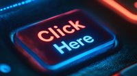 Glowing click here button in neon red and blue colors on black keyboard background with dramatic lighting and shallow depth of field effect.