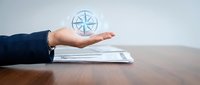 Professional businessman presenting compass navigation concept above documents on wooden desk for strategic business direction and guidance solutions.