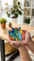 Hands holding colorful paper cutout figures representing diversity, teamwork and community support in modern office workspace for business concepts.