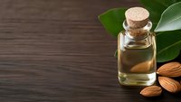 Natural almond oil in glass bottle with cork stopper, fresh almonds and green leaves on dark wooden background for skincare and aromatherapy treatments.