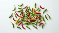 Fresh colorful chili peppers scattered on white background. Hot spicy ingredients for cooking and seasoning. Organic vegetables isolated for culinary design.