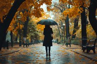 Woman in black coat holding umbrella walks alone through autumn park with golden leaves, wet pathway and moody atmosphere on rainy day.