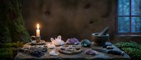 Mystical altar with crystals, candles and healing stones arranged on wooden surface in atmospheric candlelit room for spiritual meditation practices.