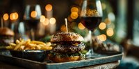 Gourmet burger with fries on wooden board in upscale restaurant setting with wine glass and warm ambient lighting for food photography and menu design.