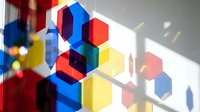 Colorful geometric hexagon shapes stacked in 3D arrangement with red, blue, and yellow blocks casting shadows on white surface for abstract design projects.