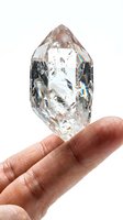 Raw diamond crystal held in hand against white background, showcasing natural facets and light refraction for jewelry, gemstone, and luxury design projects.