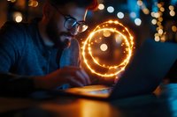 Caucasian bearded man in glasses working on laptop at night with glowing neon smile emoji circle, bokeh lights background creating magical atmosphere.