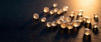 Sparkling diamonds scattered on dark wooden surface with warm golden light creating luxury jewelry and precious gemstone display for investment concepts.