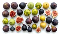 Assorted fresh figs in various stages of ripeness, whole and halved, displaying red and green flesh on white background for culinary and food styling projects.