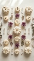 Autumn flat lay with white pumpkins, dried roses and crystals arranged on neutral background for seasonal decoration and wellness themes.