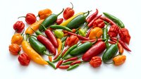 Fresh assorted hot peppers including red, orange, yellow and green varieties arranged on white background for culinary and food styling projects.