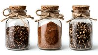 Glass jars with cork lids filled with black peppercorns and ground pepper, tied with rustic twine on white background, isolated cooking ingredients.