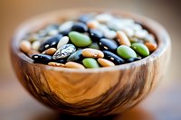 Assorted colorful legumes in wooden bowl with black, green, and beige beans for healthy cooking and nutrition concept.