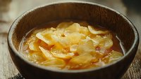 Ginger slices steeped in hot water with honey, creating a soothing golden brew served in a rustic ceramic bowl for wellness and culinary use.