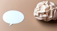 Crumpled paper ball next to empty speech bubble on beige background. Creative concept for communication, writer's block and brainstorming ideas.