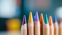 Macro shot of colorful wooden pencils arranged in row showing sharp tips against blurred background. Creative art supplies for drawing and coloring.