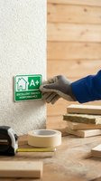 Worker hand holding green A+ energy efficiency rating label for sustainable building construction and eco-friendly home insulation materials.
