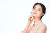 Young Asian woman in pink blouse with thoughtful expression and natural makeup poses against white background, displaying confidence and elegance.