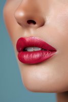 Close-up of sensual red lips with matte lipstick on light skin tone against turquoise background, showing partial nose and clean professional makeup application.