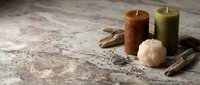 Lit candles in autumn tones with driftwood and cream sphere on marble surface, creating warm ambiance for home decor, wellness, and seasonal styling projects.