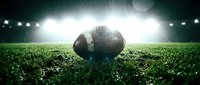 Professional football on grass field under stadium lights with dramatic atmosphere for sports marketing and game day promotions.