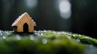 Miniature wooden house on moss covered ground with morning dew drops and bokeh lights in dark forest setting, creating magical fairy tale atmosphere.