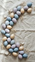 Pastel colored Easter eggs arranged in decorative pattern with dried flowers on neutral linen fabric background for spring holiday celebration and festive decor.