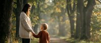 Young mother and toddler son holding hands walking together on peaceful autumn park path surrounded by golden sunlight and mature trees.