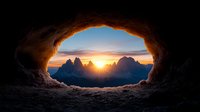 Dramatic sunrise view through natural rock arch window overlooking majestic mountain peaks silhouetted against colorful dawn sky in Dolomites alpine landscape.