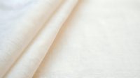 Folded cream linen fabric with soft texture and natural wrinkles, suitable for textile, fashion, and interior design projects.