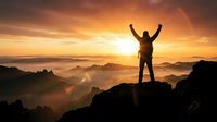 Silhouette of triumphant hiker with raised arms celebrating success on mountain peak at golden sunrise with misty valleys below.