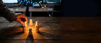 Businessman hand protecting glowing light bulbs on wooden table with bokeh background, representing business growth, innovation, and success strategy.