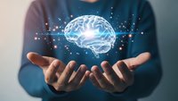 Person holding glowing digital brain hologram with neural network connections representing artificial intelligence, machine learning and cognitive technology innovation.