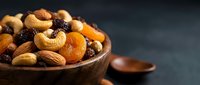Mixed nuts and dried fruits in wooden bowl on dark background, healthy snacking and organic food concept for nutrition and wellness lifestyle.