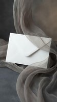 White envelope wrapped in flowing gray fabric creating elegant romantic atmosphere for wedding invitations and correspondence.