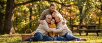 Multigenerational family enjoying outdoor picnic together in park during golden hour autumn season.