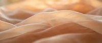 Soft, flowing fabric with warm peachy tones creates elegant waves and folds, suitable for textile, fashion, and design projects.