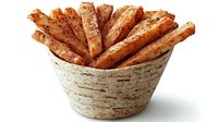 Crispy seasoned potato wedges arranged in rustic ceramic bowl on white background, isolated food photography for menu and restaurant promotion.