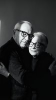 Loving senior couple embracing in black and white portrait, elderly man and woman wearing glasses showing affection and togetherness in romantic pose.