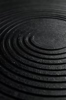 Abstract black textured surface with concentric circular ridges creating ripple effect pattern for modern design backgrounds and industrial concepts.