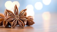 Star anise pods on wooden surface with soft bokeh background, aromatic spice macro photography showing detailed texture and natural brown tones.